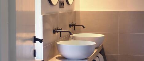 A bathroom with two white sinks, a black faucet, and a towel rack.
