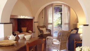 Un coin repas avec une table en bois dressée pour quatre personnes, une chaise en osier et un canapé.