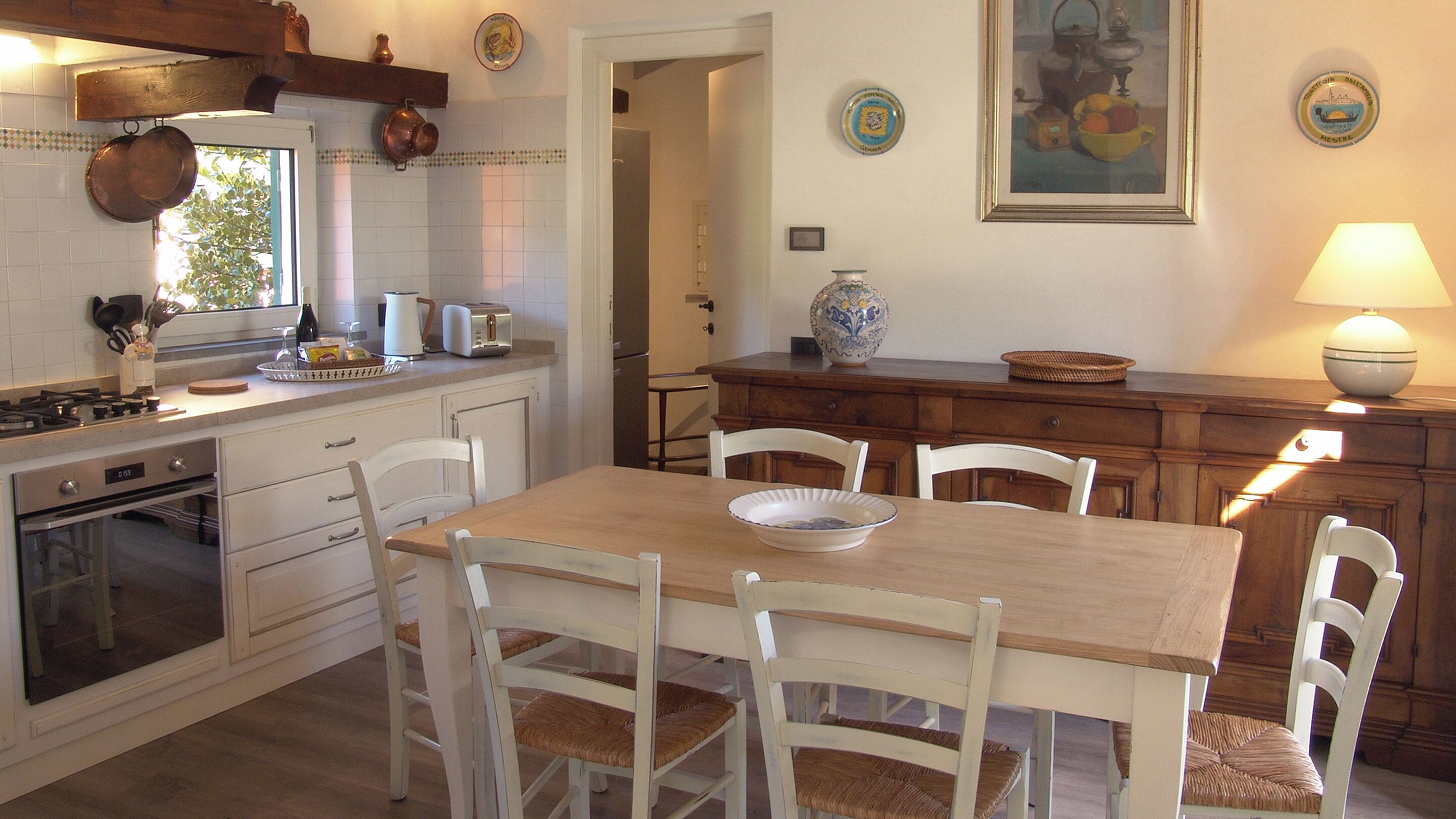 Una cocina con una mesa de madera, sillas blancas y una estufa.