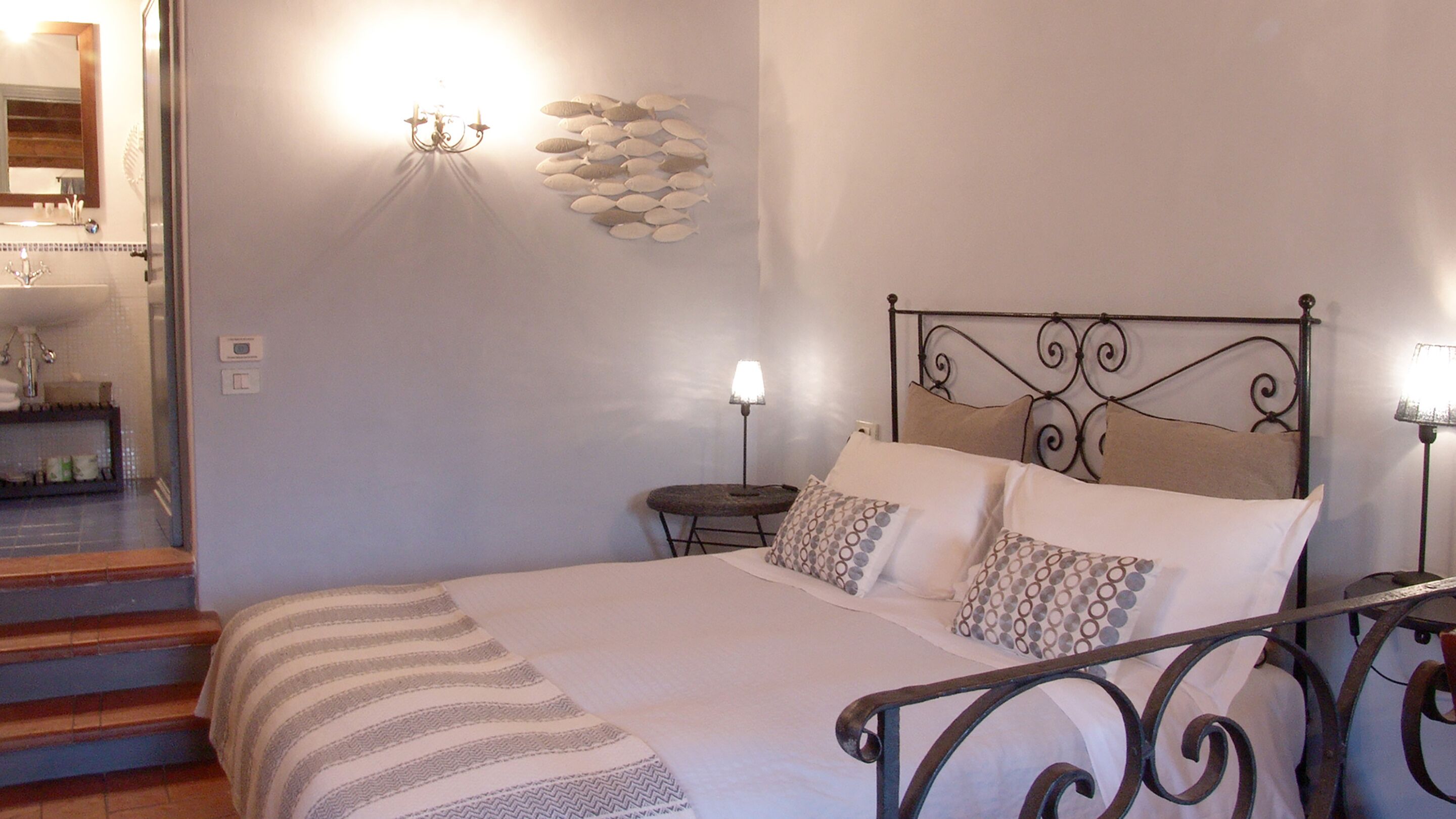 Een slaapkamer met een bed, een nachtkastje, een wandlamp, een spiegel en een trap.