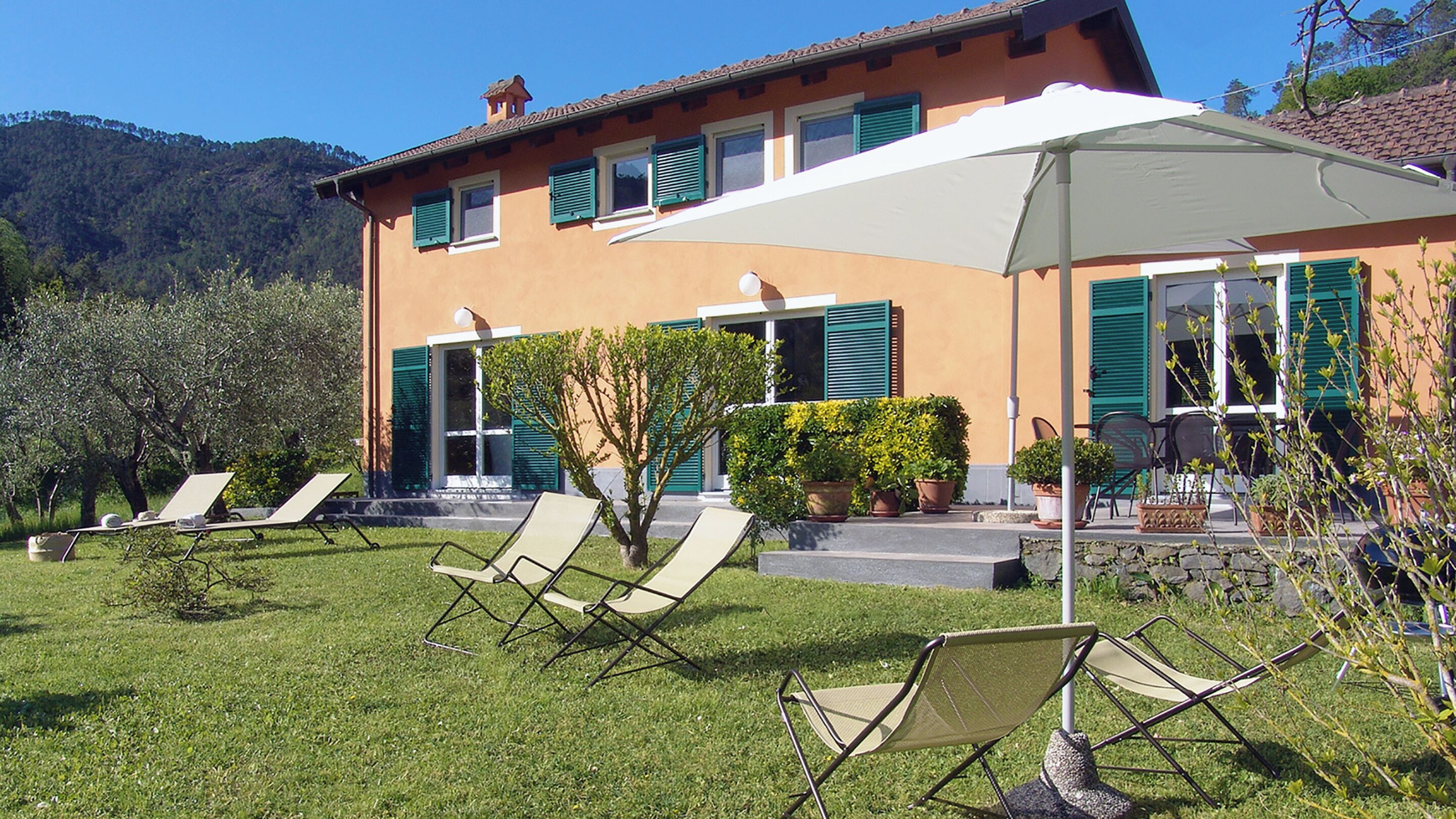 A house with a garden, outdoor seating, and a large umbrella.