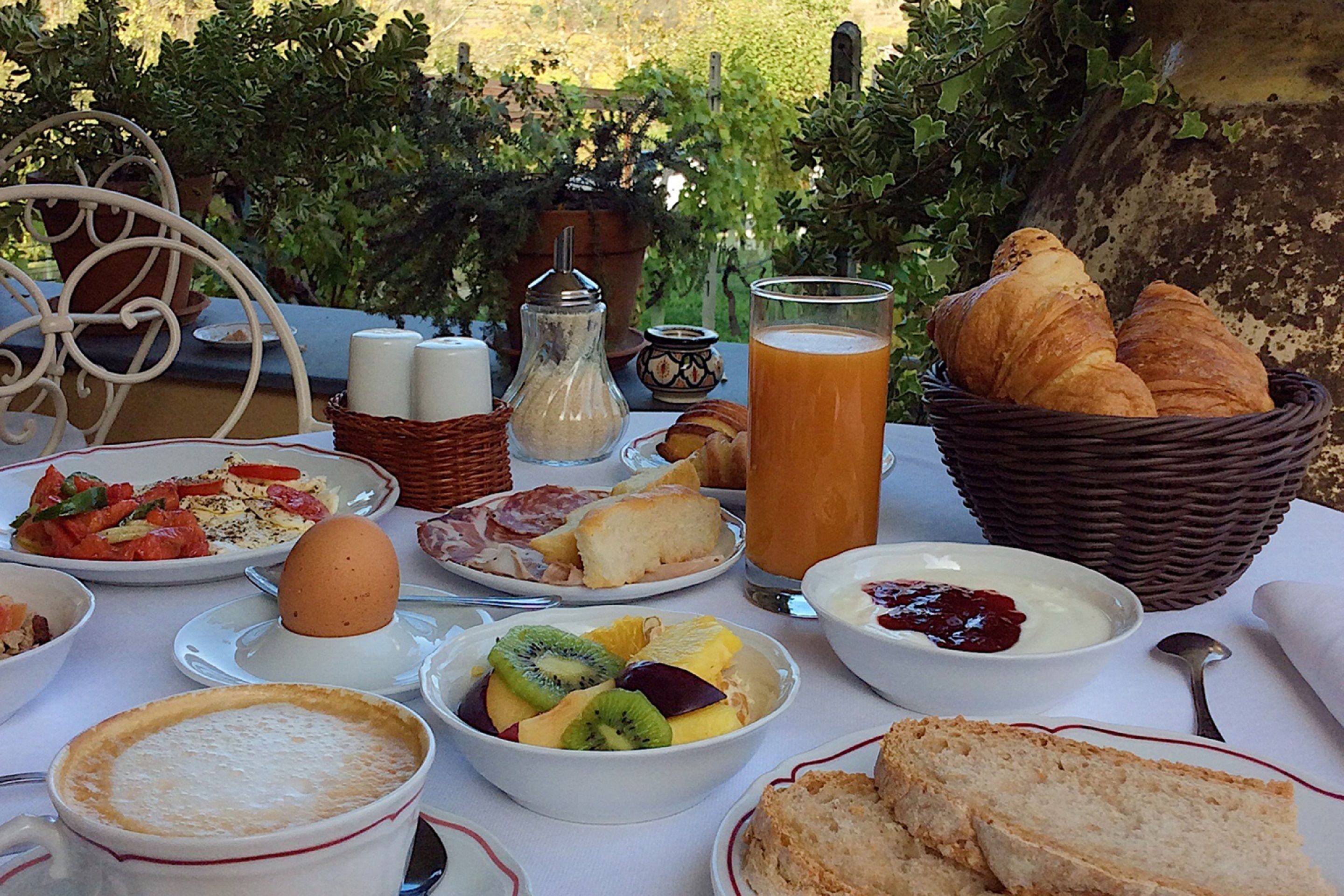 A breakfast table with various dishes, including eggs, bread, and fruit.
