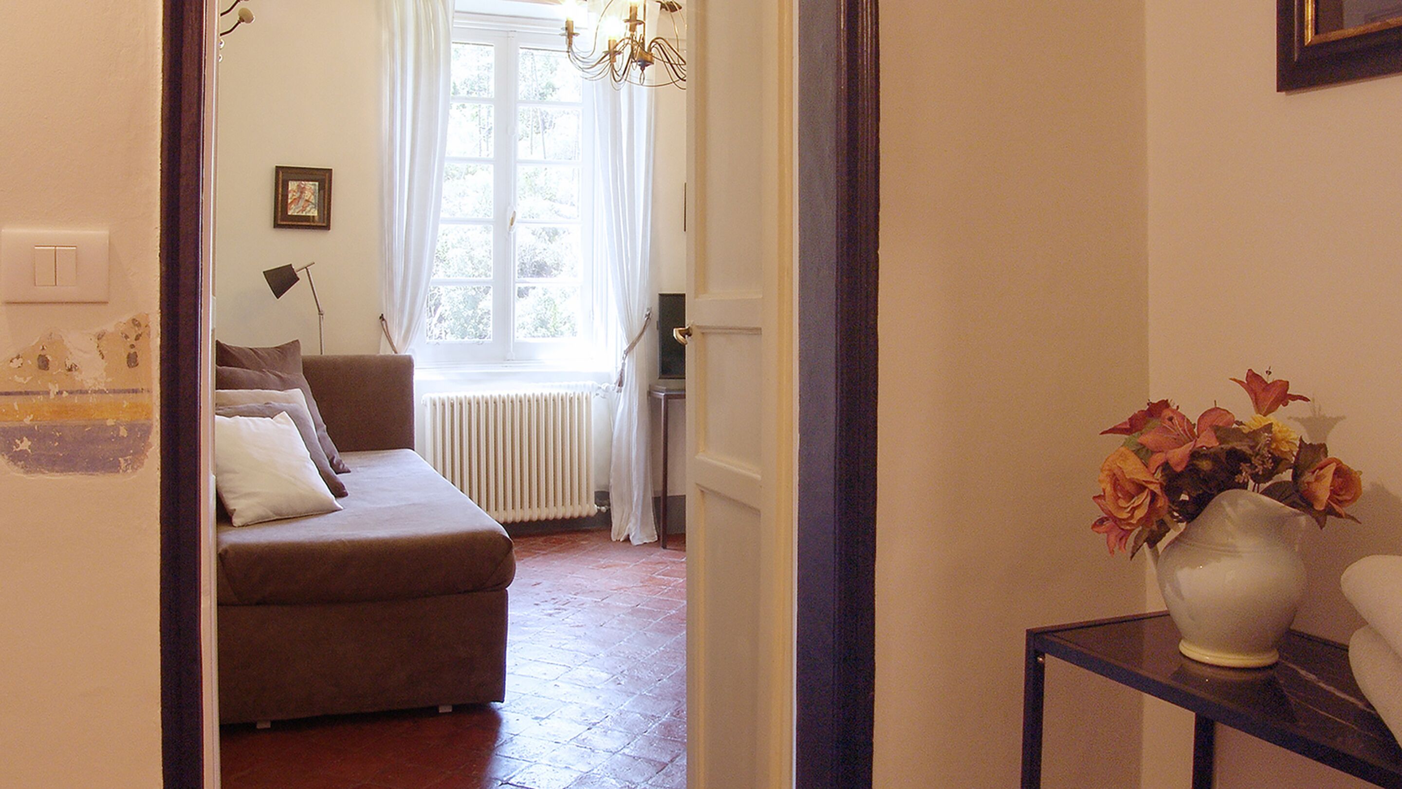 Ein gemütliches Wohnzimmer mit einer braunen Couch, einem Heizkörper und einem Fenster mit Vorhängen.