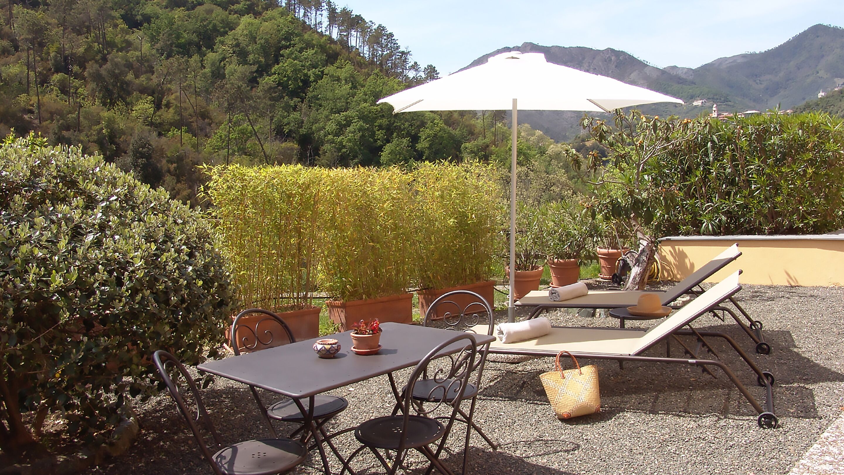 An outdoor patio with a table and chairs, a sun umbrella, and lounge chairs.