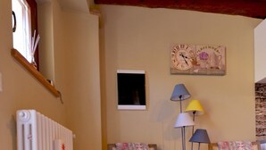 A cozy room with two armchairs, a patterned rug, a radiator, and a basket. - Casa Rosalba - WelcHome (Cannobio)