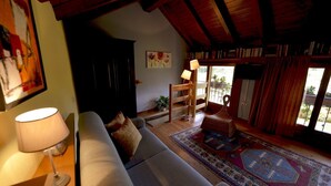 A cozy living room with a sofa, a lamp, a bookshelf, and a large window with curtains. - Casa Rosalba - WelcHome (Cannobio)