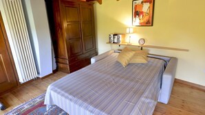A bedroom with a bed, wooden wardrobe, radiator, and a painting on the wall. - Casa Rosalba - WelcHome (Cannobio)