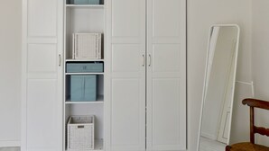 Una habitación con un armario blanco, un espejo y una silla de madera.