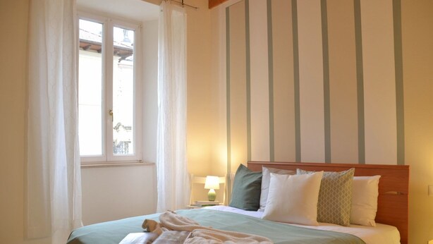 Ein Hotelzimmer mit Bett, einem Fenster mit Vorhängen, einer Nachttischlampe und rauen Tapeten.