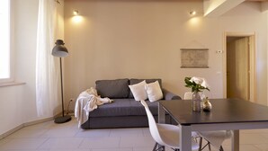 Ein modernes Wohnzimmer mit grauem Sofa, weißem Sessel und einem Esstisch.