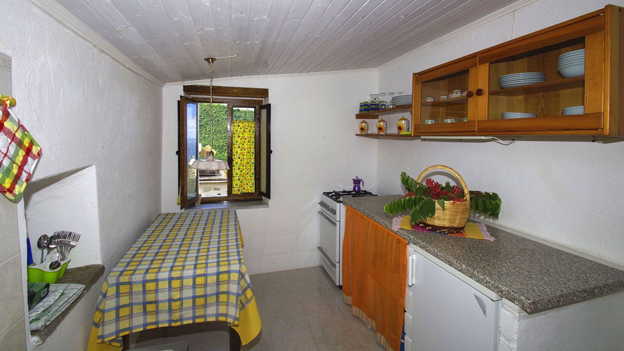 A compact kitchen with a dining table, a window with a view, and a wooden cabinet above the counter.