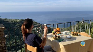 Una persona disfrutando de una comida en un balcón con vistas panorámicas al mar y las colinas.