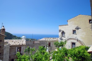 A coastal town with traditional architecture, including a building with a tiled roof and another with a bell tower. - EcoBelmonte Albergo Diffuso (Belmonte Calabro)