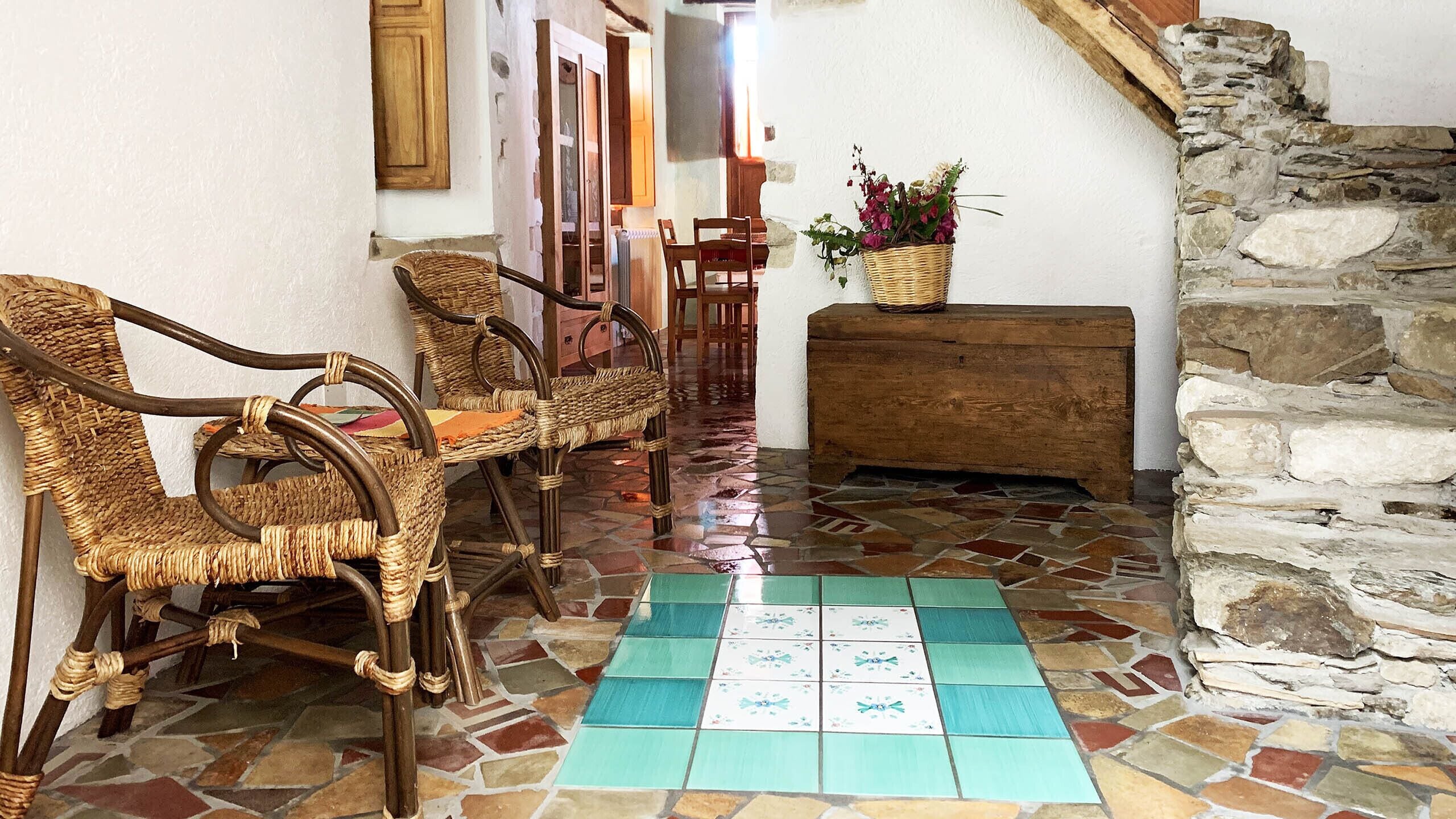 Quarto com móveis de vime, parede de pedra e chão de azulejos.