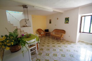 A dining area with a table set for two, a wicker sofa, and a small table with chairs. - EcoBelmonte Albergo Diffuso (Belmonte Calabro)