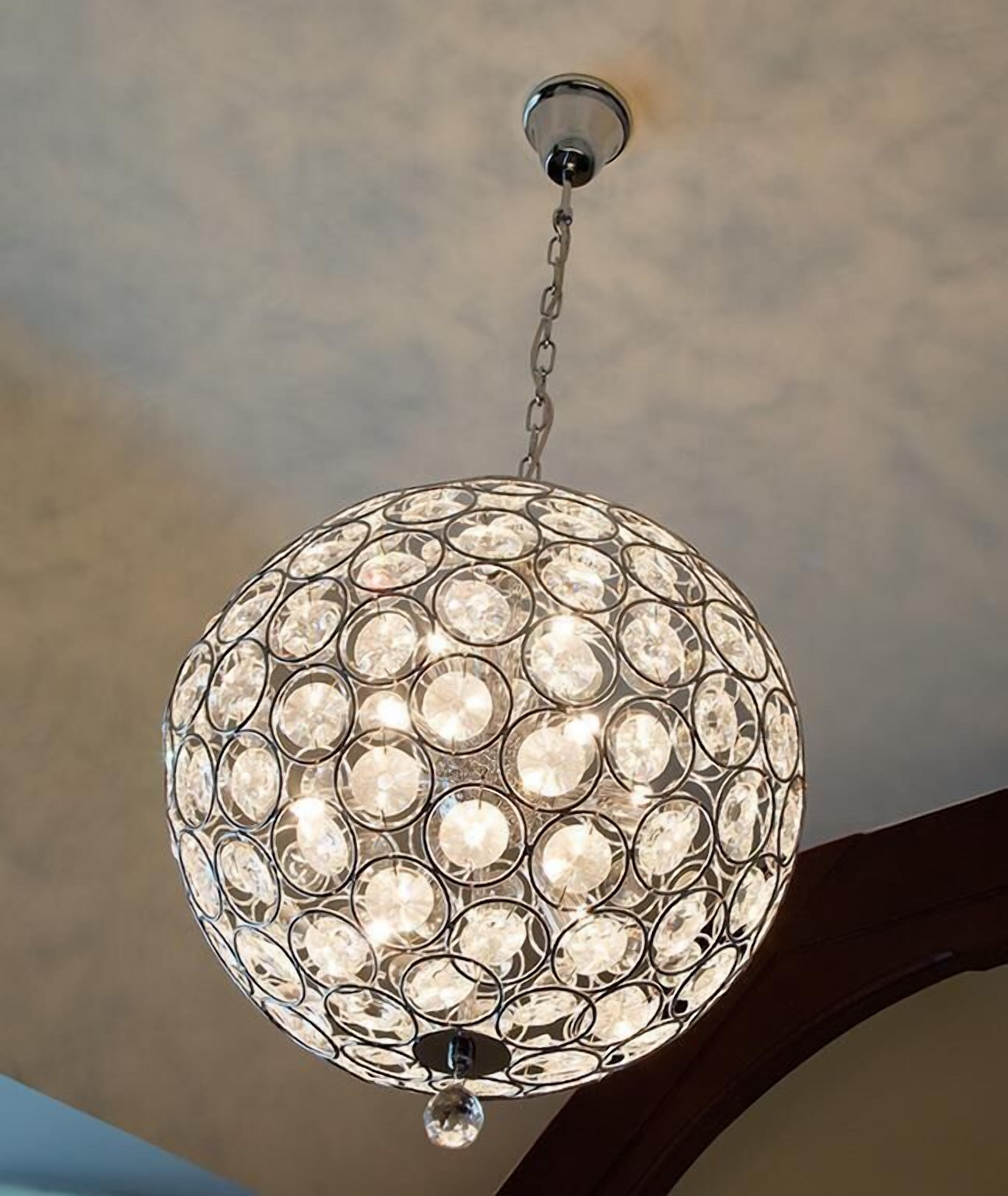 A spherical chandelier with multiple clear crystal elements, hanging from a ceiling fixture.