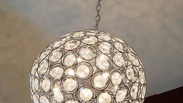 A spherical chandelier with multiple clear crystal elements, hanging from a ceiling fixture.