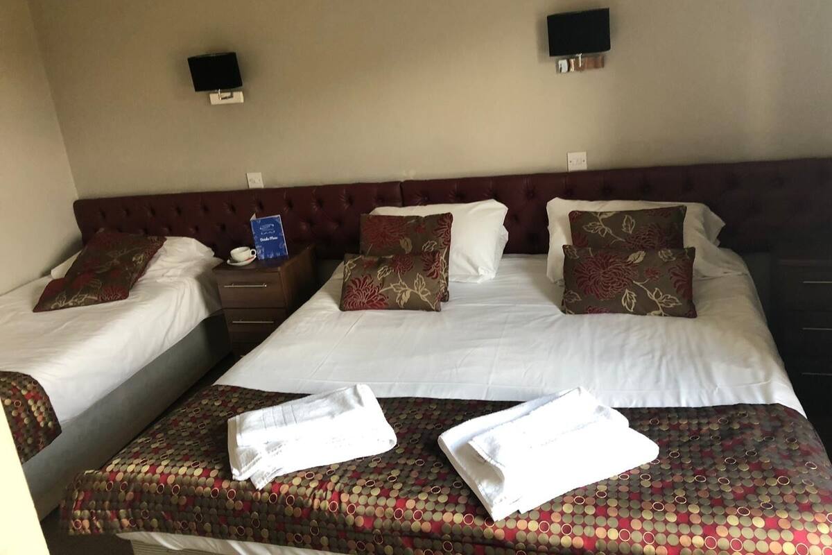 A hotel room with two beds, a nightstand, and a wall-mounted TV.