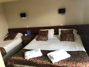 A hotel room with two beds, a nightstand, and a wall-mounted TV.