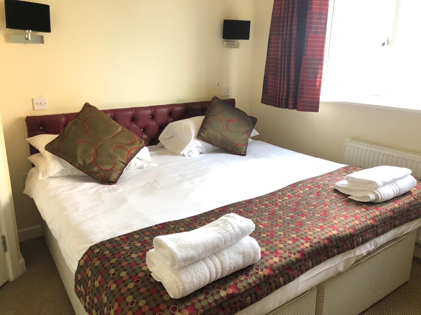 A neatly made bed with white linens, a patterned bedspread, and two pillows with a circular design.