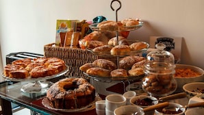 A buffet table with various baked goods, including pastries and muffins, and a jar of cookies. - B&B Cascina Belmonte (Fossano)