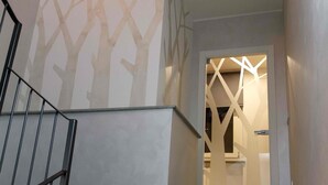 A staircase with a geometric wall design, a door with a modern light fixture, and a metal railing. - B&B Cascina Belmonte (Fossano)