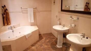 Une salle de bain avec une baignoire, deux lavabos et des toilettes.