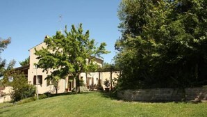 A two-story building with a sloped roof, surrounded by a well-maintained lawn and mature trees. - Agriturismo La Barca nel Bosco (Fano)