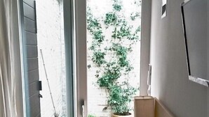 A room with a wooden desk, a chair, a TV mounted on the wall, and a view of a garden through an open door. - Agriturismo La Barca nel Bosco (Fano)