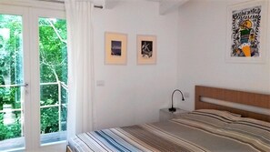 A bedroom with a bed, a nightstand, a window with curtains, and two framed pictures on the wall. - Agriturismo La Barca nel Bosco (Fano)