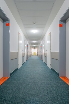 Pitkä, kapea käytävä, jossa on ovet numeroilla 507 ja 508, lattialla on matto ja seinät ovat valkoiset.