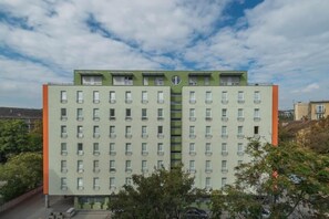 Monikerroksinen rakennus, jonka julkisivu on symmetrinen ja jossa on tasaisin välein sijoitettuja ikkunoita sekä keskellä oleva pyöreä elementti.