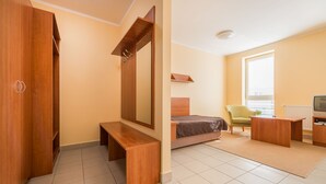 Ein Schlafzimmer mit einem Bett, einem Holzschrank, einer Bank, einem Schreibtisch, einem Stuhl und einem Fernseher.