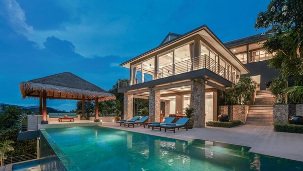 A modern two-story house with a large swimming pool, a thatched-roof gazebo, and multiple lounge chairs. - Baan Kimsacheva (Koh Samui)