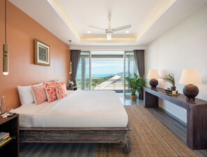 Habitación de hotel moderna con una cama grande, ventilador de techo, vista al océano y balcón.