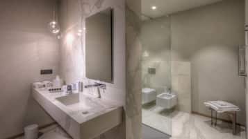 Un baño moderno con un espejo grande, dos lavamanos, ducha con mampara de vidrio y encimera de mármol.