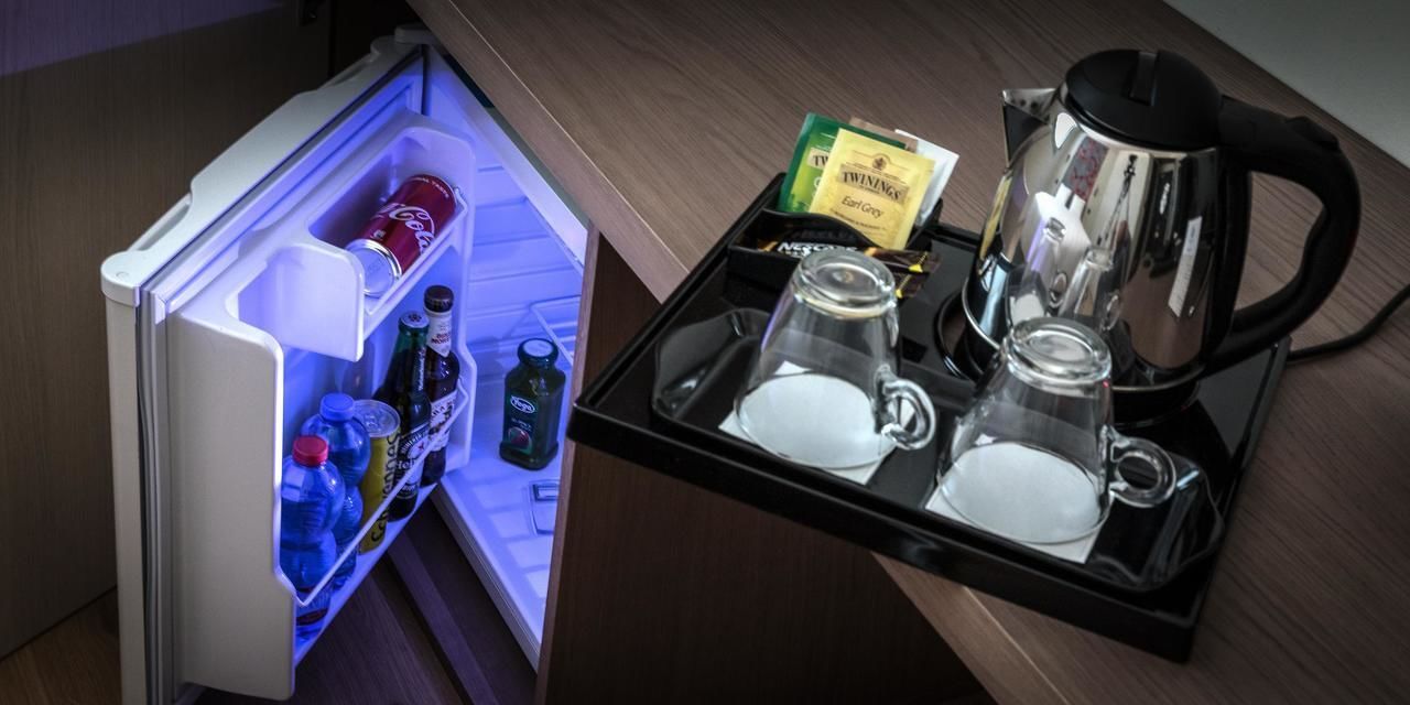 Ein Kühlschrank mit einer Ablage, auf der ein Glas, ein Wasserkocher und eine Packung Twinings Earl Grey Tee stehen.