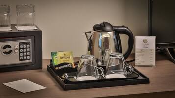 A hotel minibar setup with a coffee maker, two glasses, a tray, and Twinings Earl Grey tea packets.