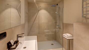Un baño moderno con ducha acristalada, lavamanos blanco y un perchero para toallas.