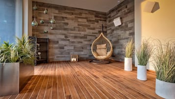 A modern room with a hanging chair, wooden flooring, and potted plants.
