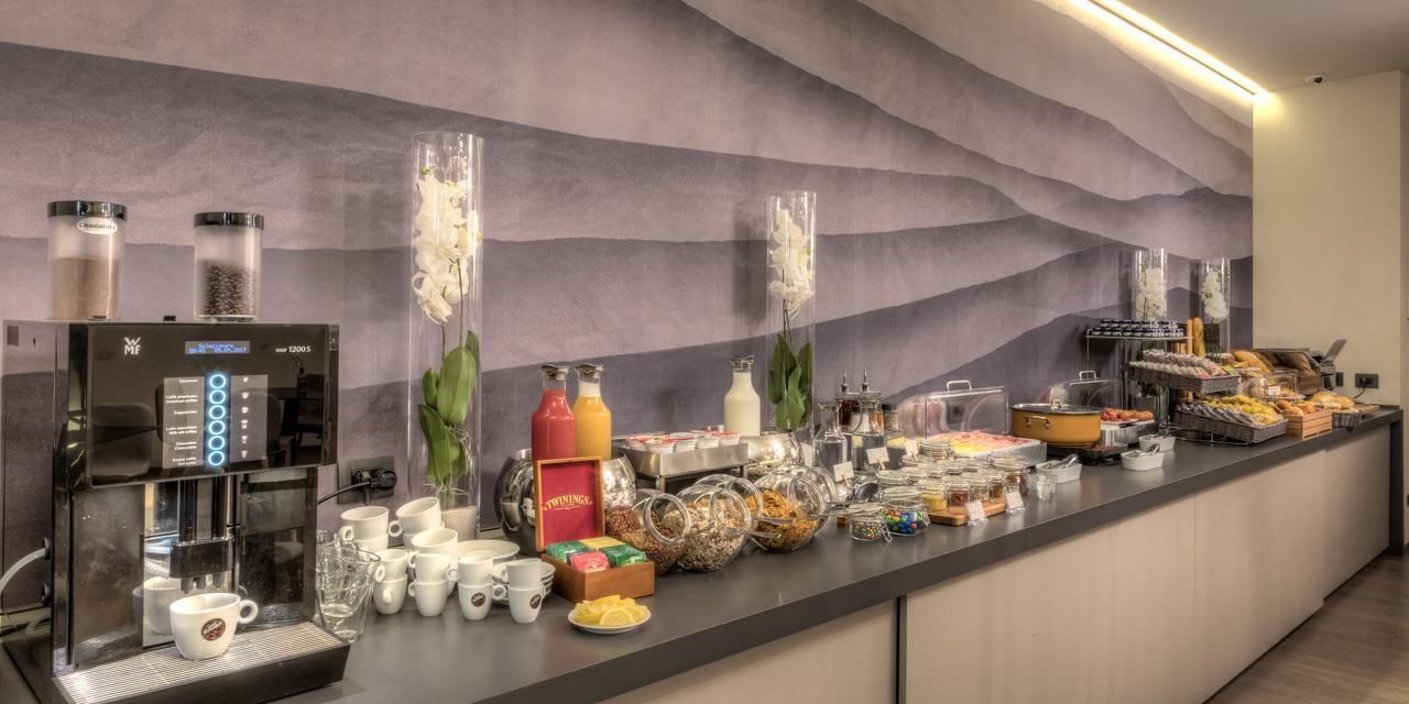A breakfast buffet with a coffee machine, various food items, and condiments.