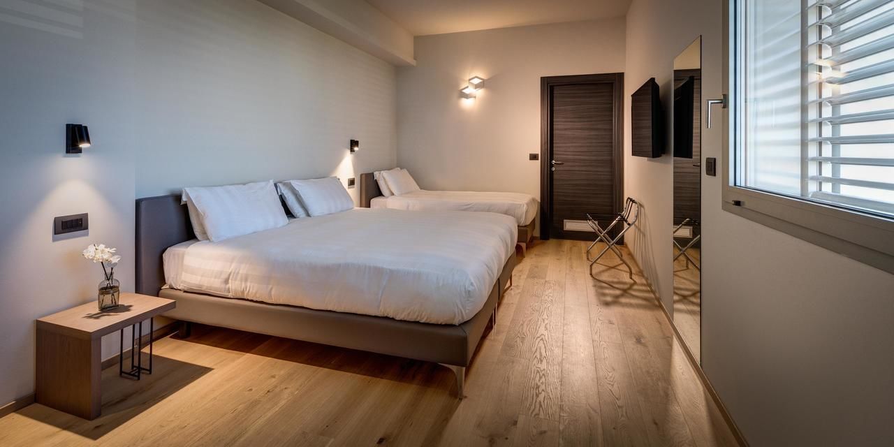 Ein Schlafzimmer mit zwei Betten, einem Nachttisch, einem Spiegel und einem Fenster mit Jalousien.