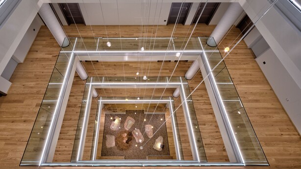 Un moderno atrio con una estructura de vidrio central y piso de madera.