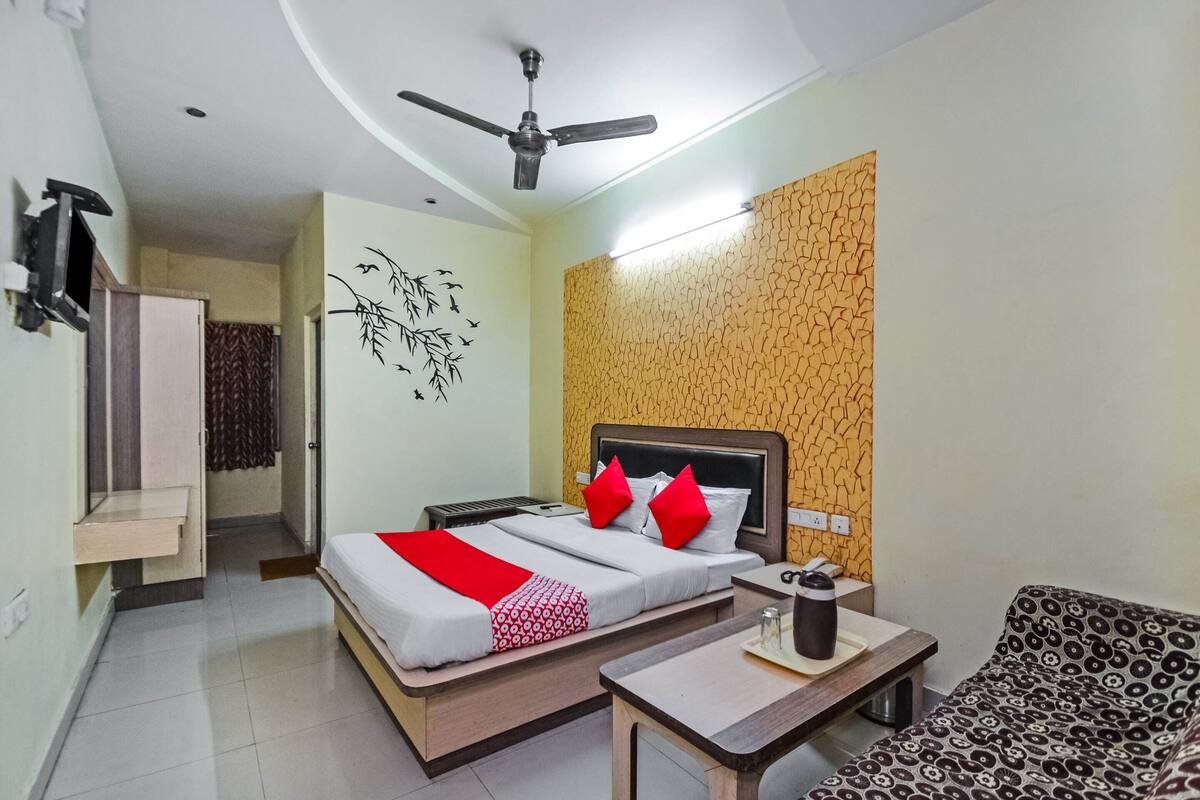 A hotel room with a bed, bedside table, and a sofa.