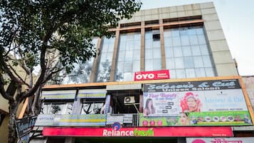 A building with multiple commercial establishments including a hotel named OYO Hotel Prince, a salon, and a pest control service.