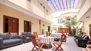 A spacious indoor area with a high ceiling, furnished with sofas, chairs, and a round table. - RedDoorz Plus near STIE YKPN (Depok)