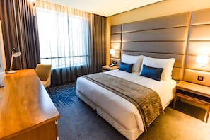 A hotel room with a large bed, a desk, a chair, a nightstand, and a lamp. - Hotel 2 Février Lomé Appartement (Lomé)