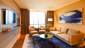 Una sala de estar moderna con un sofá, dos sillones, una mesa de centro y un televisor montado en la pared.