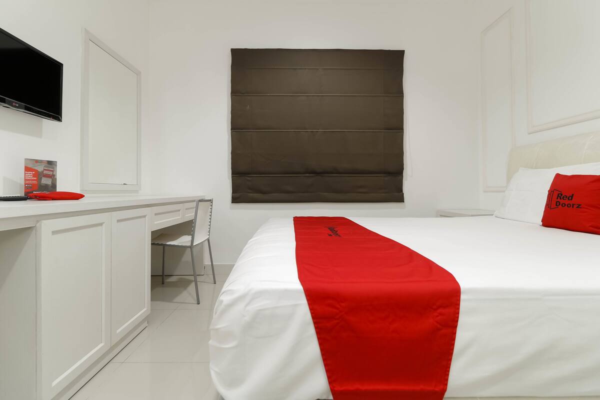 A hotel room with a bed, a desk, and a chair.