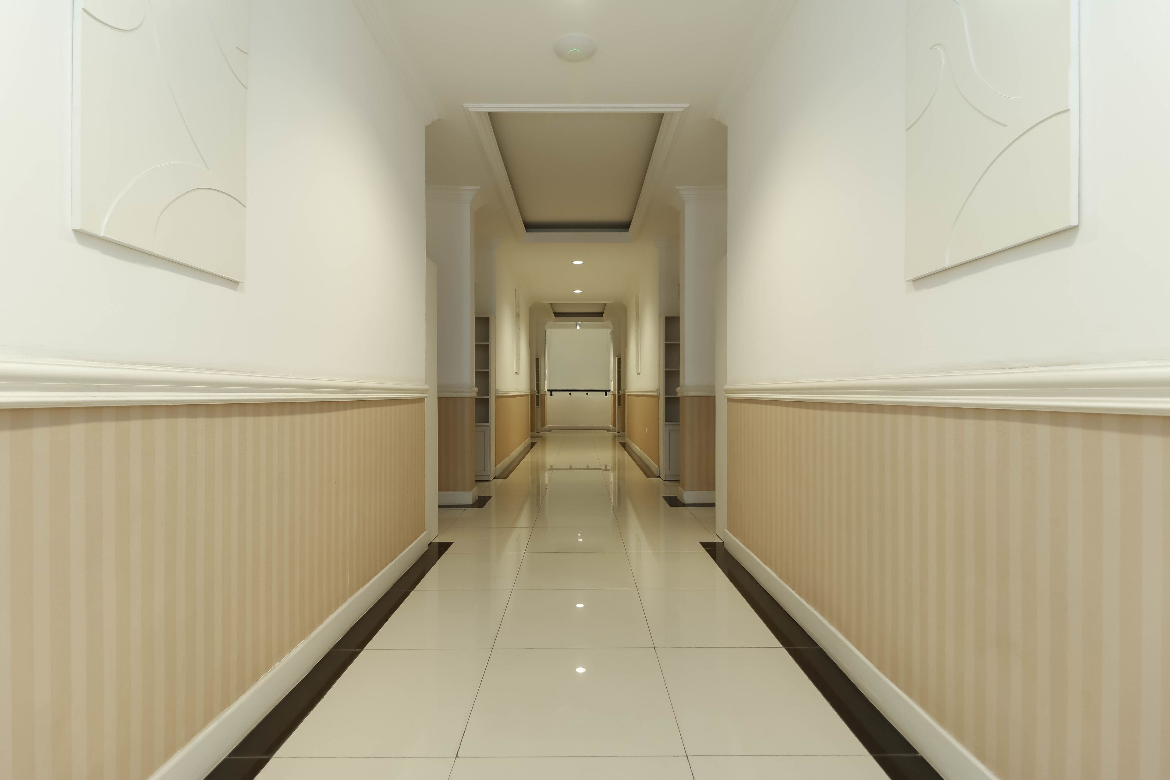A long, narrow hallway with a tiled floor and striped wall paneling.